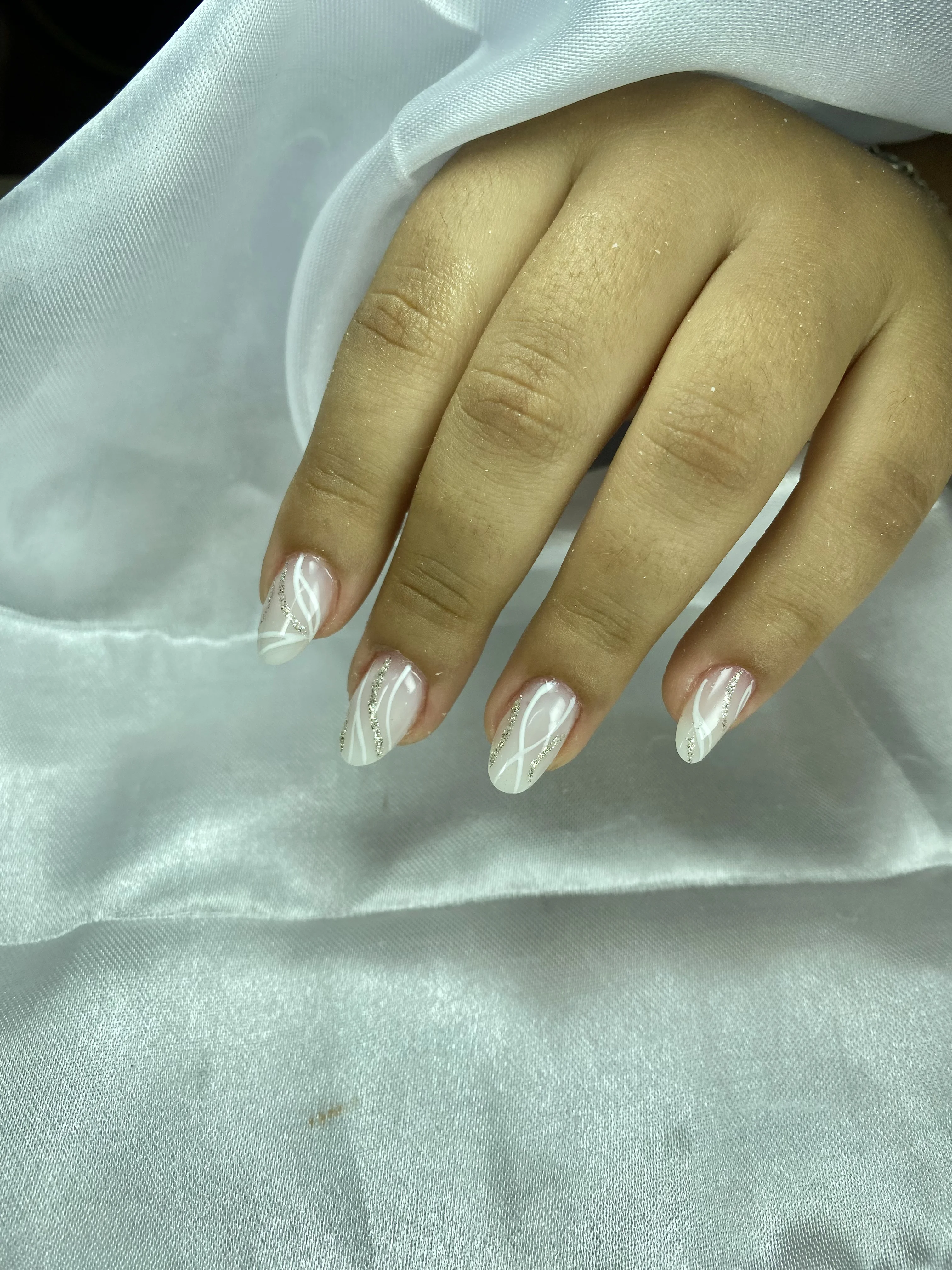 Unhas almond com nail art geométrica branca sobre tecido acetinado — design exclusivo Joice Souza